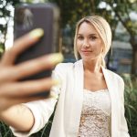 Beautiful young blonde businesswoman using smartphone in the city