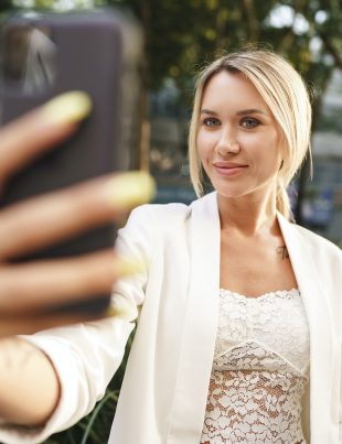 Beautiful young blonde businesswoman using smartphone in the city