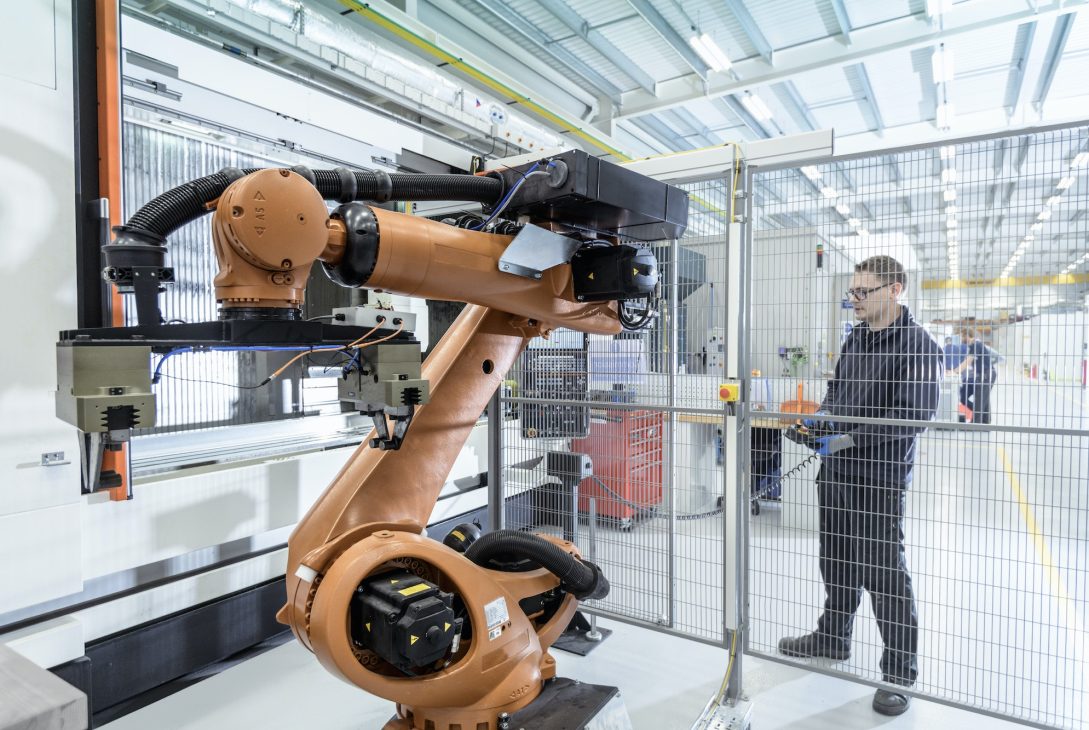 Robotics engineer operating robot aided CNC machine in robotics research facility