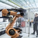 Robotics engineer operating robot aided CNC machine in robotics research facility